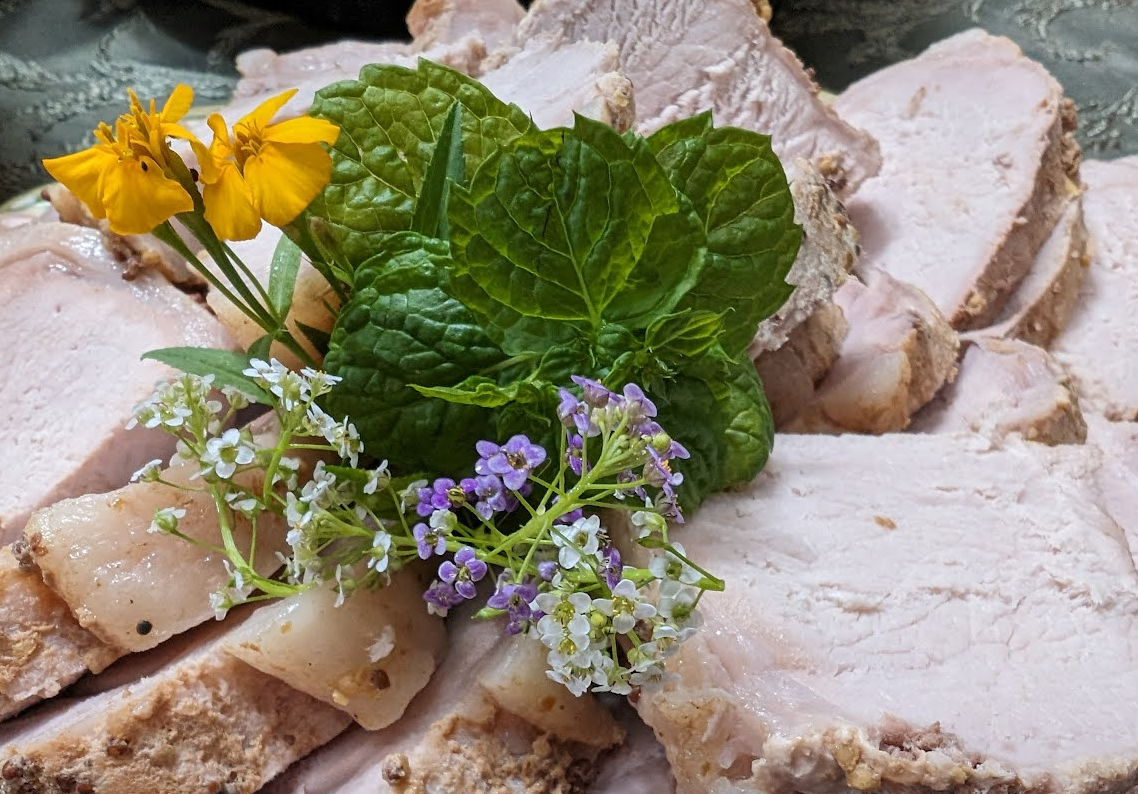 Slow-cooked pork loin garnished with edible flowers