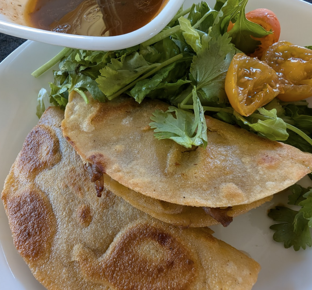 two birria tacos on a white plate